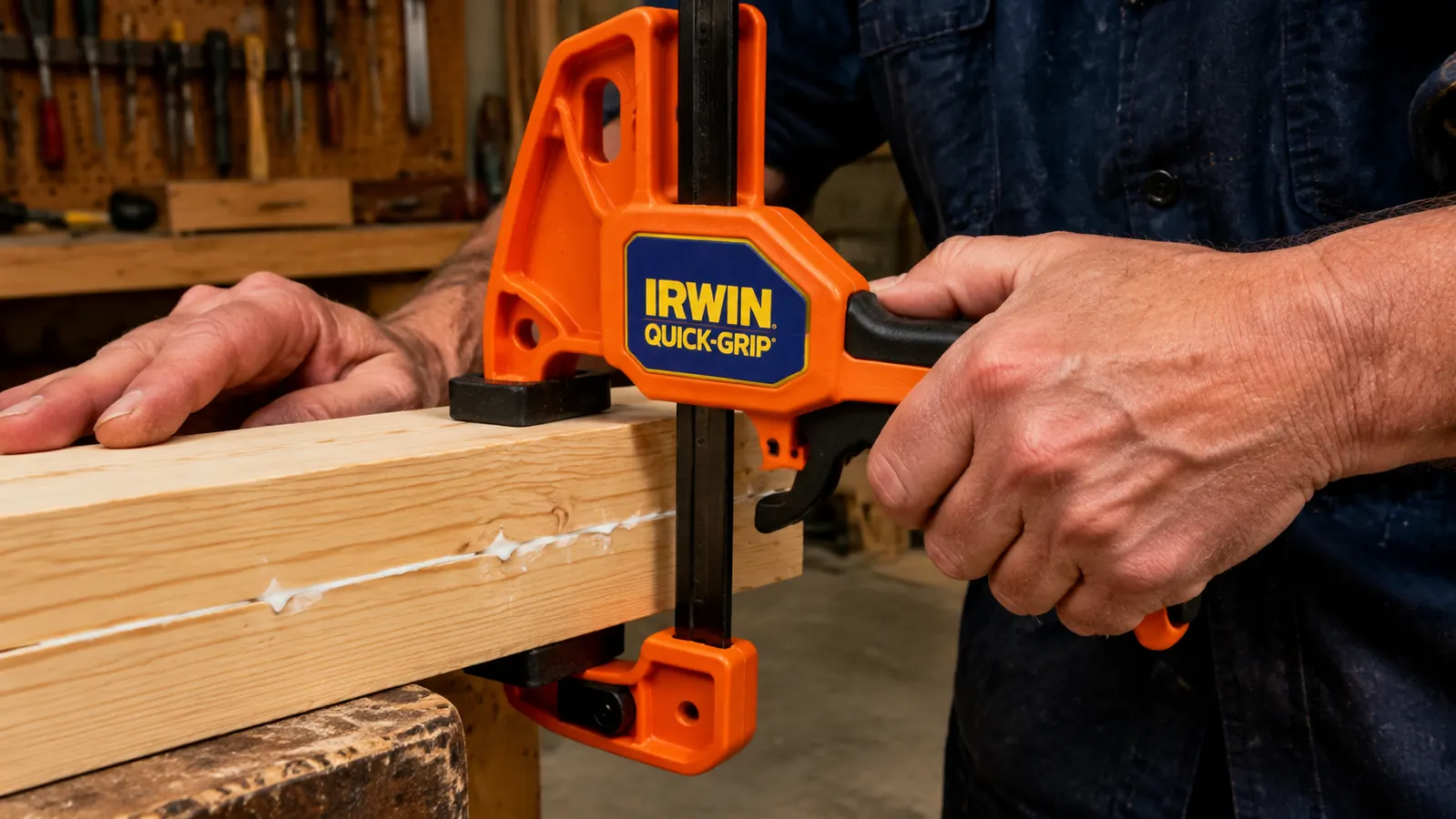One hand squeezing an IRWIN Quick-Grip clamp closed over a glue joint on edge-glued pine boards