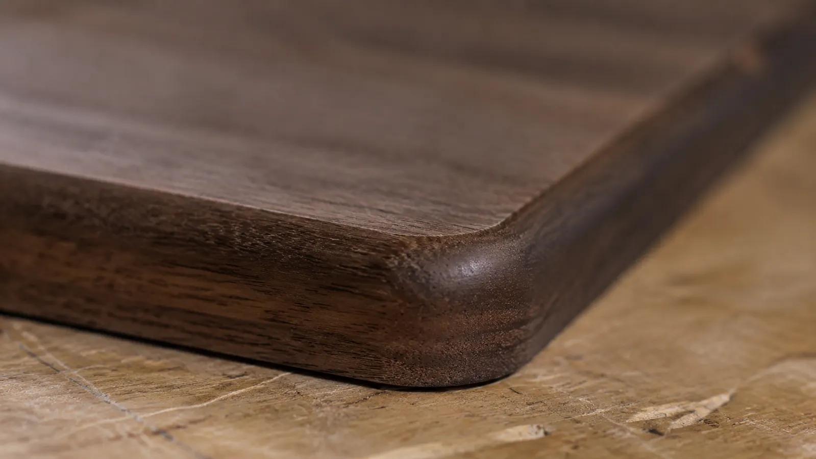 Close-up of a clean, burn-free round-over edge profile on a solid walnut board