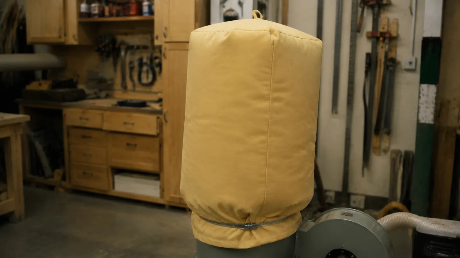 WEN dust collector bag expanded and full of fine sawdust shavings inside a home garage shop