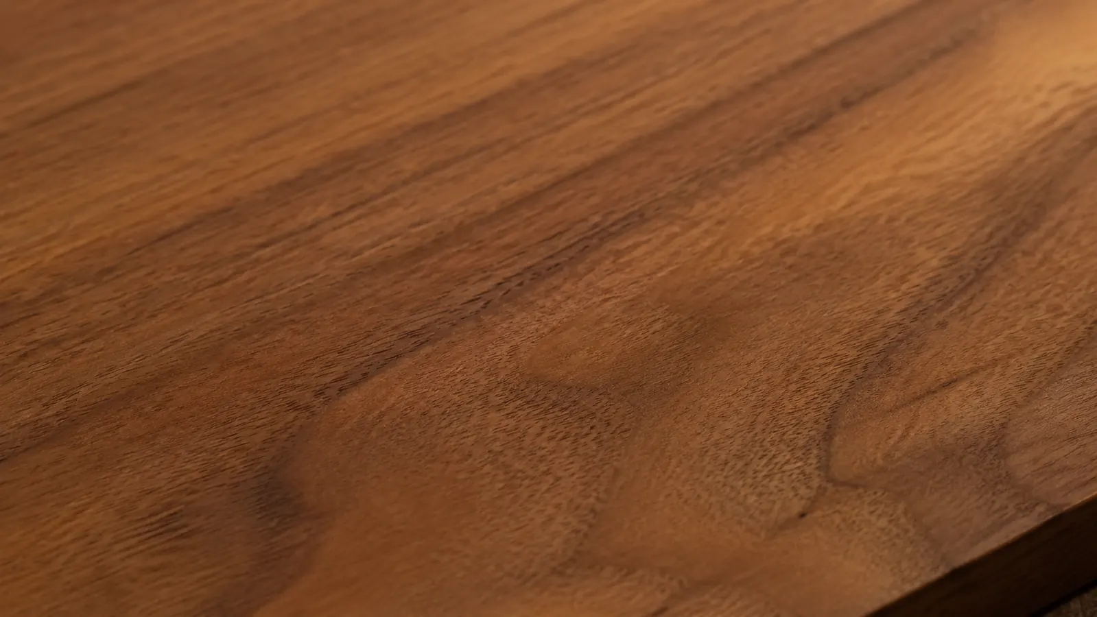Close-up of a smooth walnut surface after finish sanding, grain visible, ready for the first coat